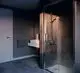 Duschbereich mit einem idealen Standardsystem, Glasduschkabine und verchromtem Duschthermostat. Gepflasterter Boden und moderne Waschbeckenanlage im Hintergrund.